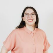 Lauren's headshot. She has long dark hair and is wearing glasses and a shirt buttoned up to her neck.