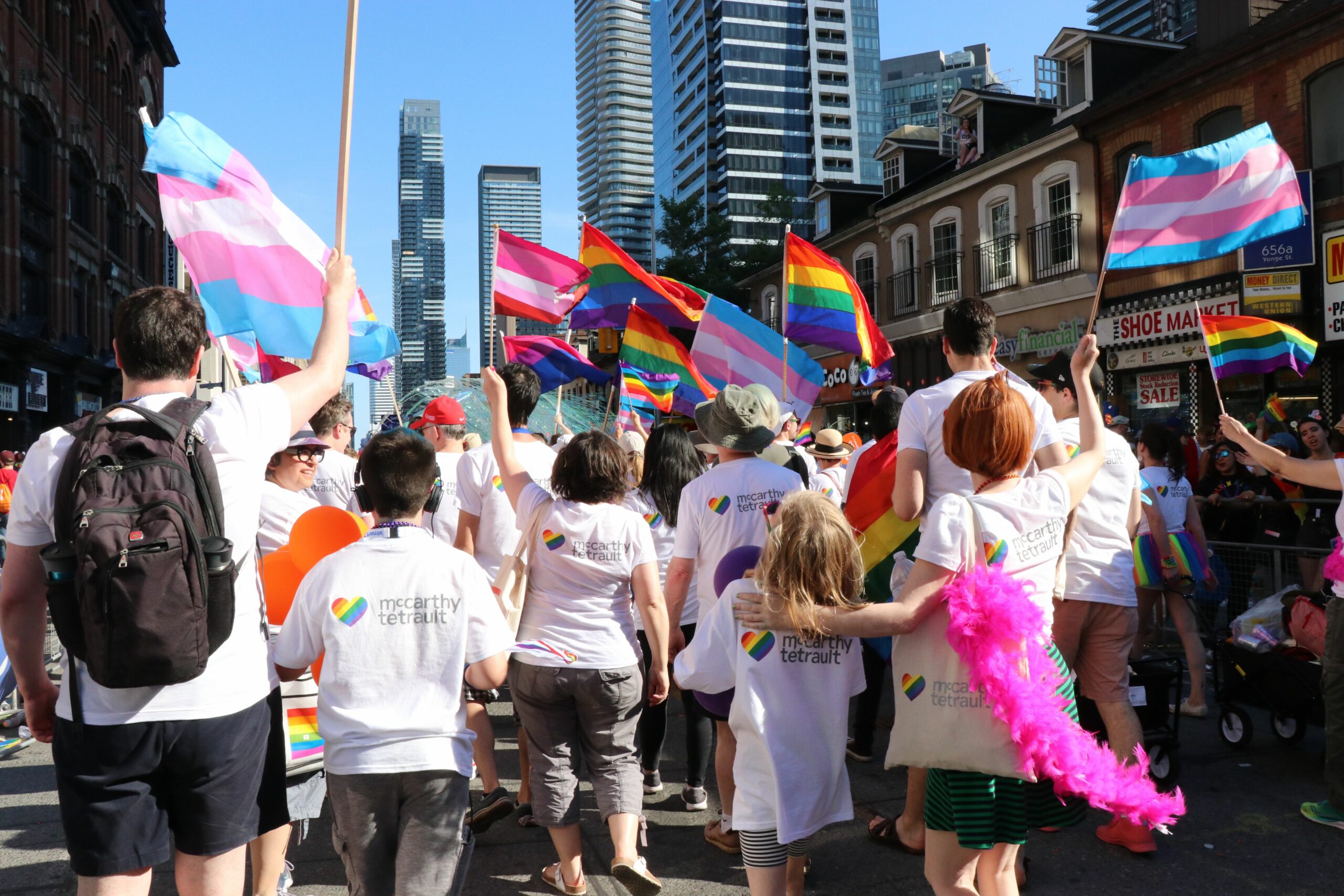 People marching during Pride in Toronto bearing 2SLGBTQIA and trans flags.