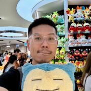 Headshot of Ting-Fai smiling posing behind a stuffed Snorlax.