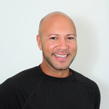 Trystan smiling in front of a neutral background.
